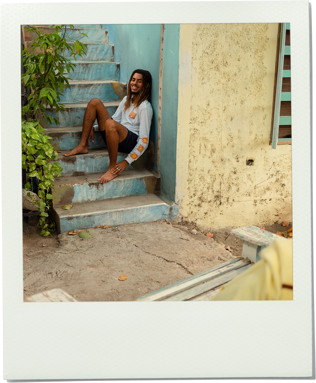 Man sitting on a staircase with a plant and wall in the background