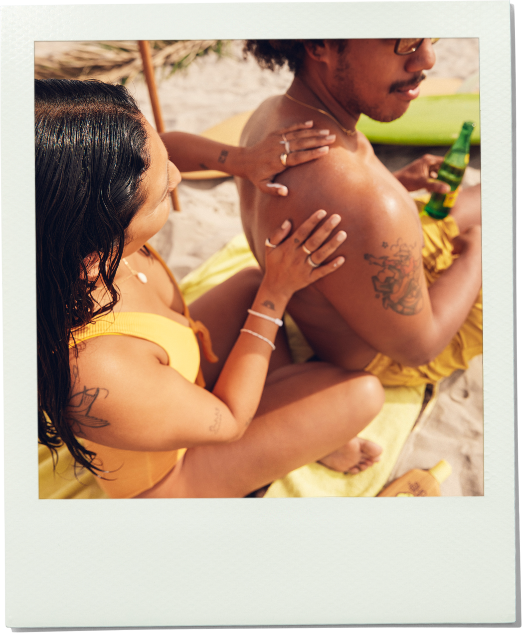 Two people on a beach with one person holding a bottle.