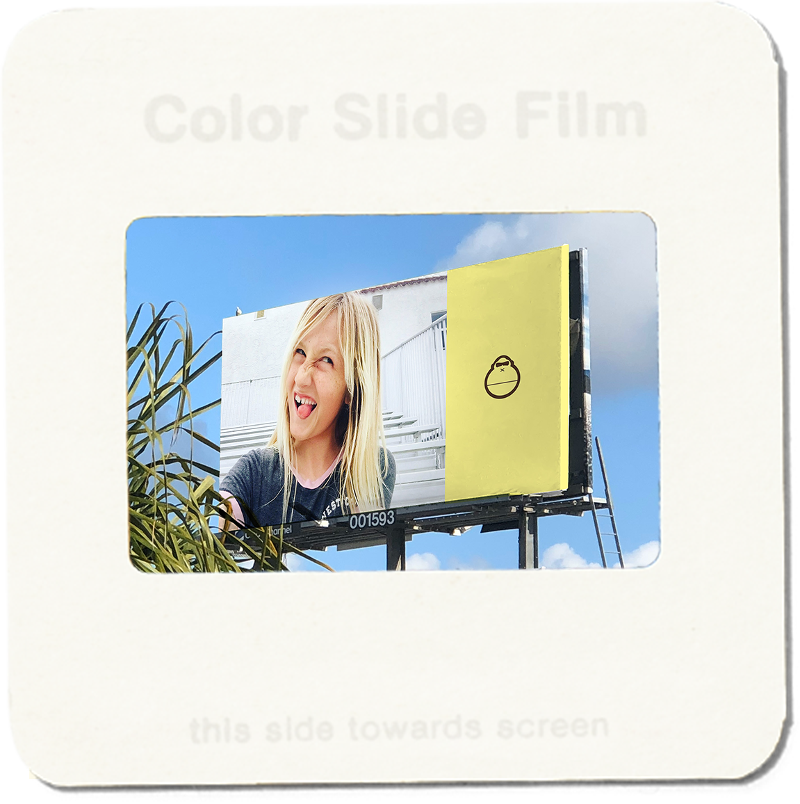 Color slide film with a photo of a woman on a billboard and a yellow box.