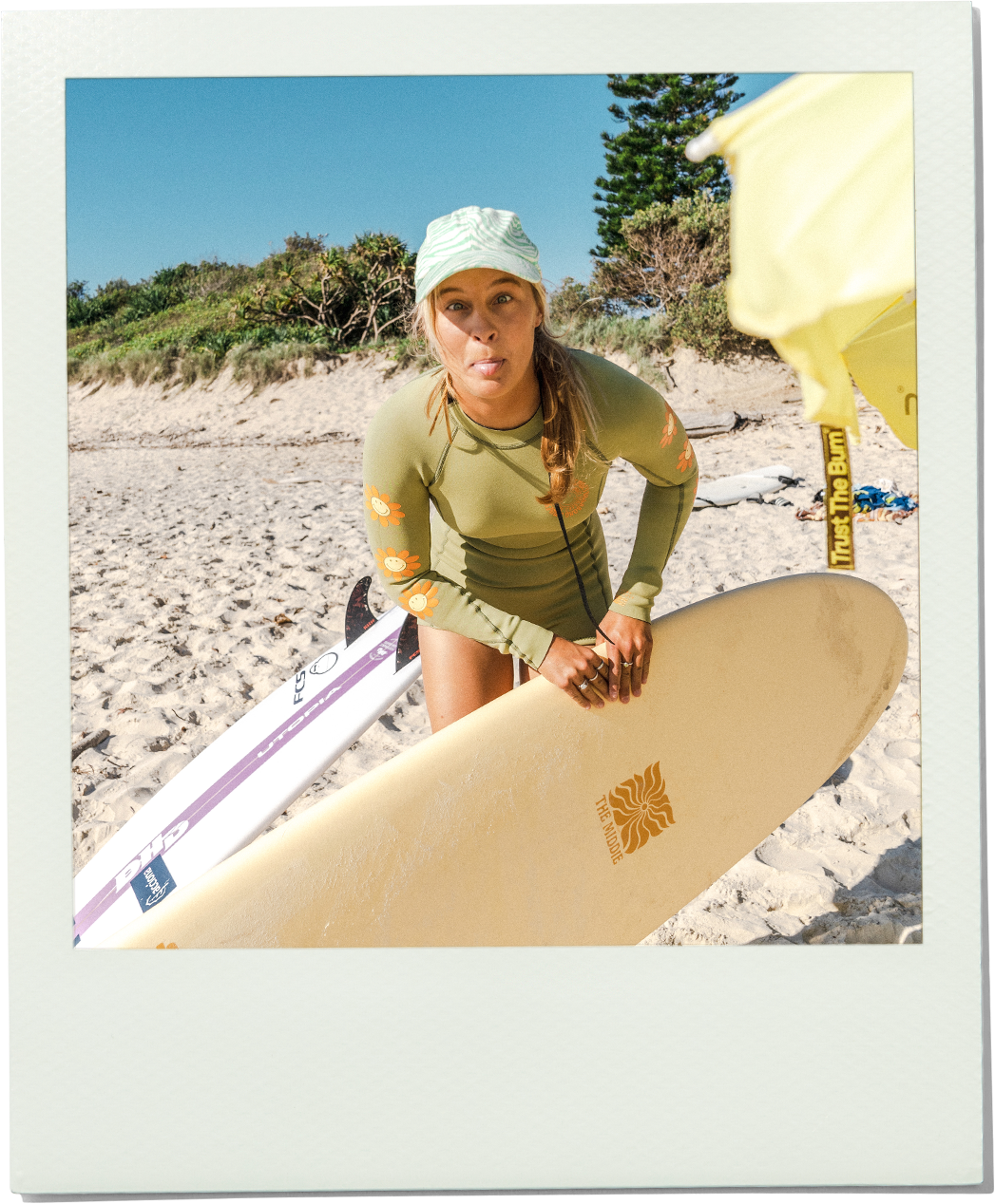Person holding a surfboard on a beach with a clear sky