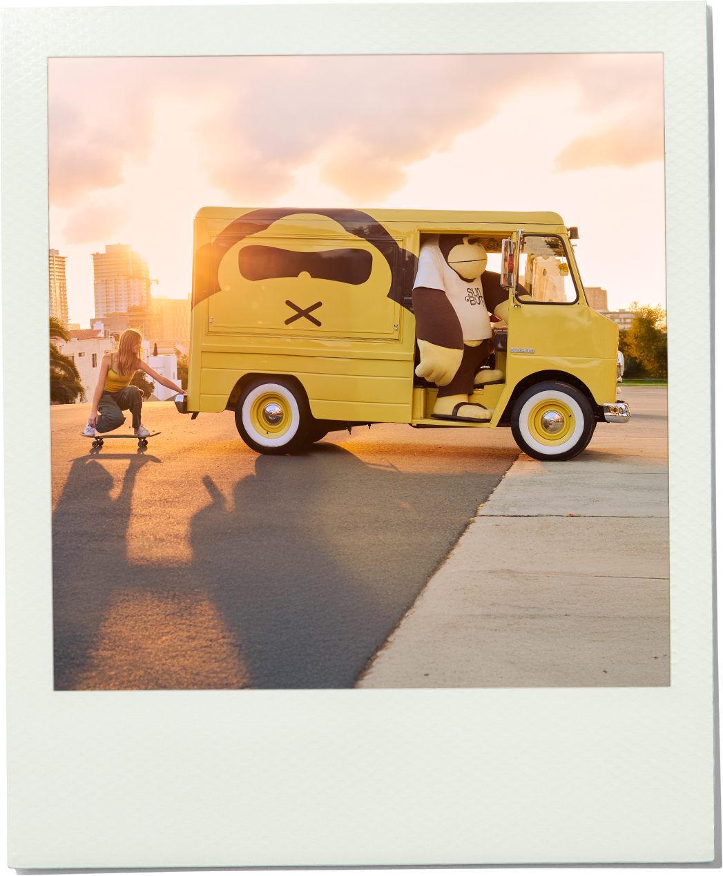 Yellow van with a person inside, skateboarding on a sidewalk at sunset.