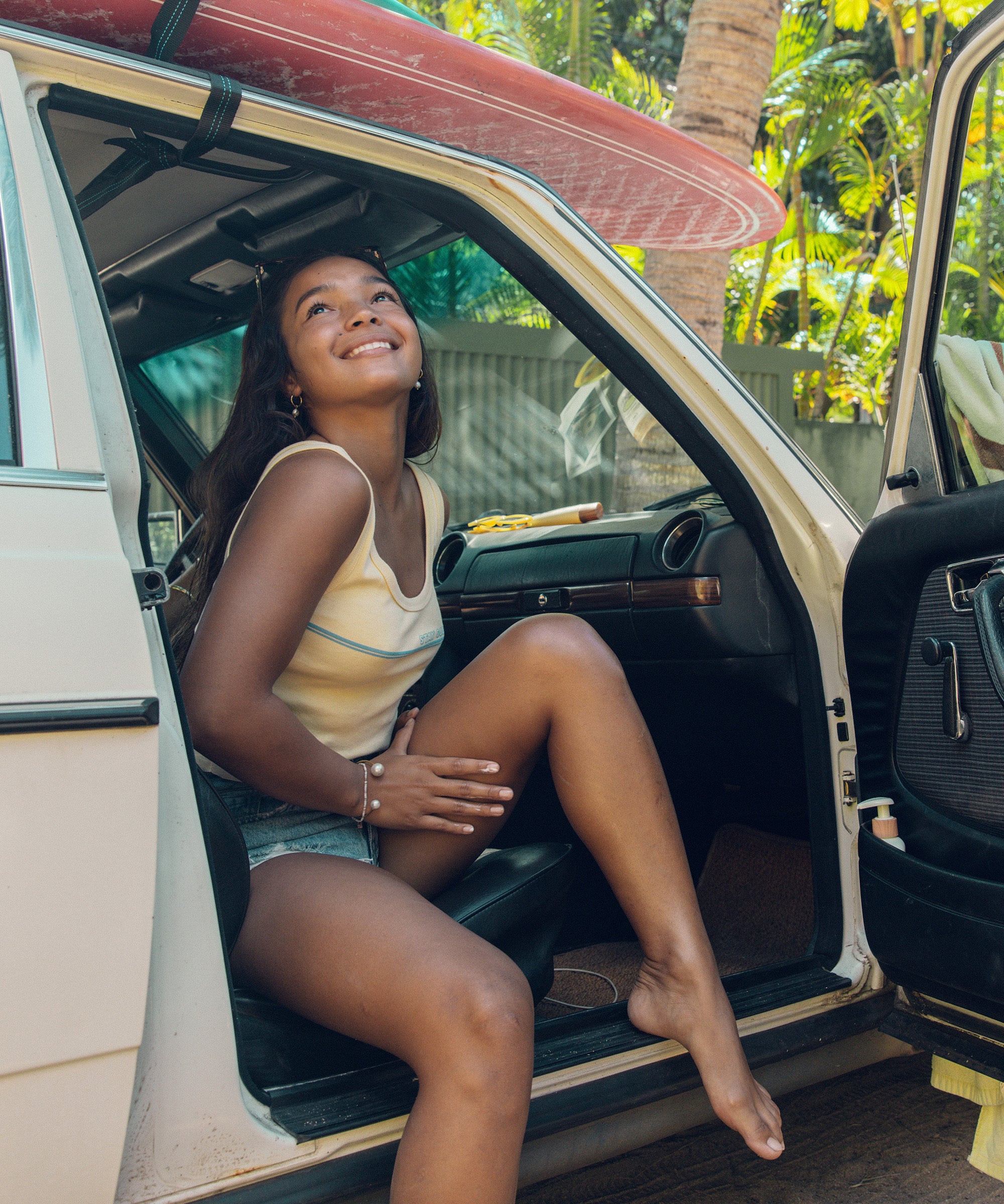 Woman applying Daily 50 Body Lotion while sitting in a car, ready for a sun-filled adventure, Sun Bum