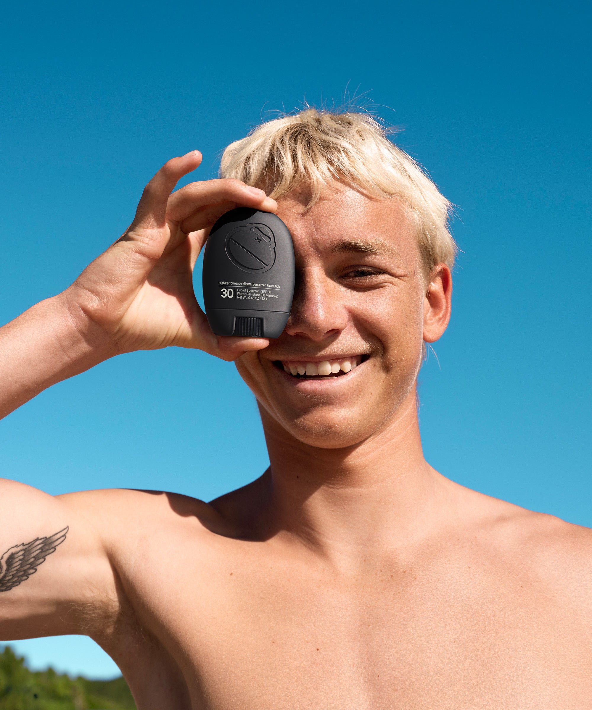 Person holding Sun Bum's Higher Performance Mineral Sunscreen Face Stick in his hand over his face