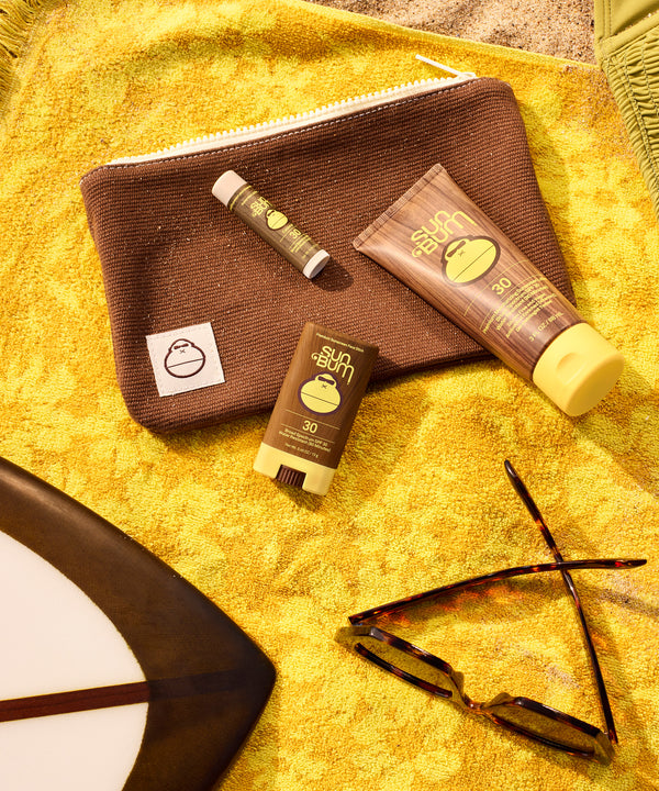 Road Tripper travel kit with essential sun care products on yellow beach towel - Sun Bum