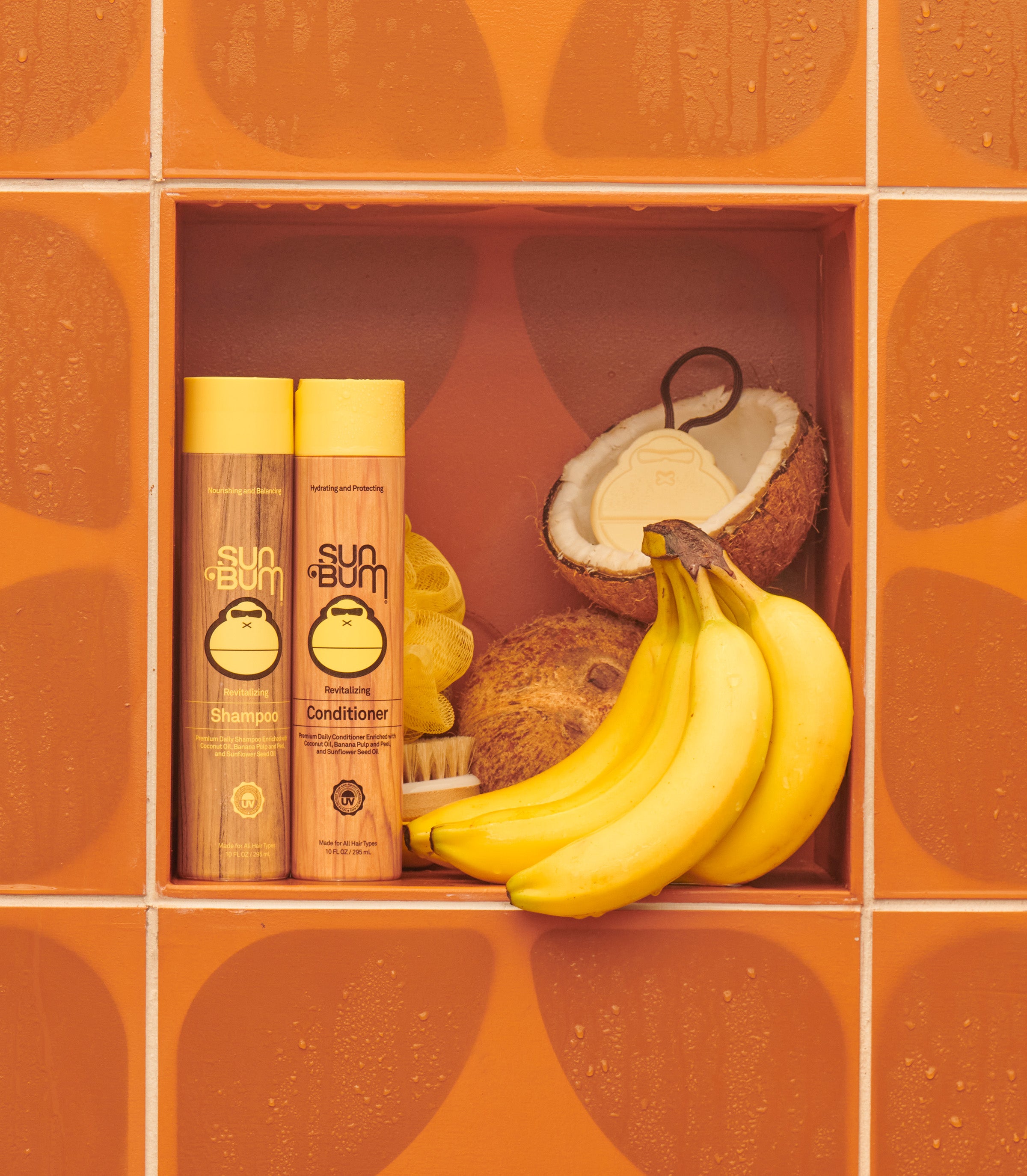 Sun Bum Revitalizing Shampoo and Conditioner with bananas and coconut in a tiled shower nook – Wholesale Collection - Sun Bum.