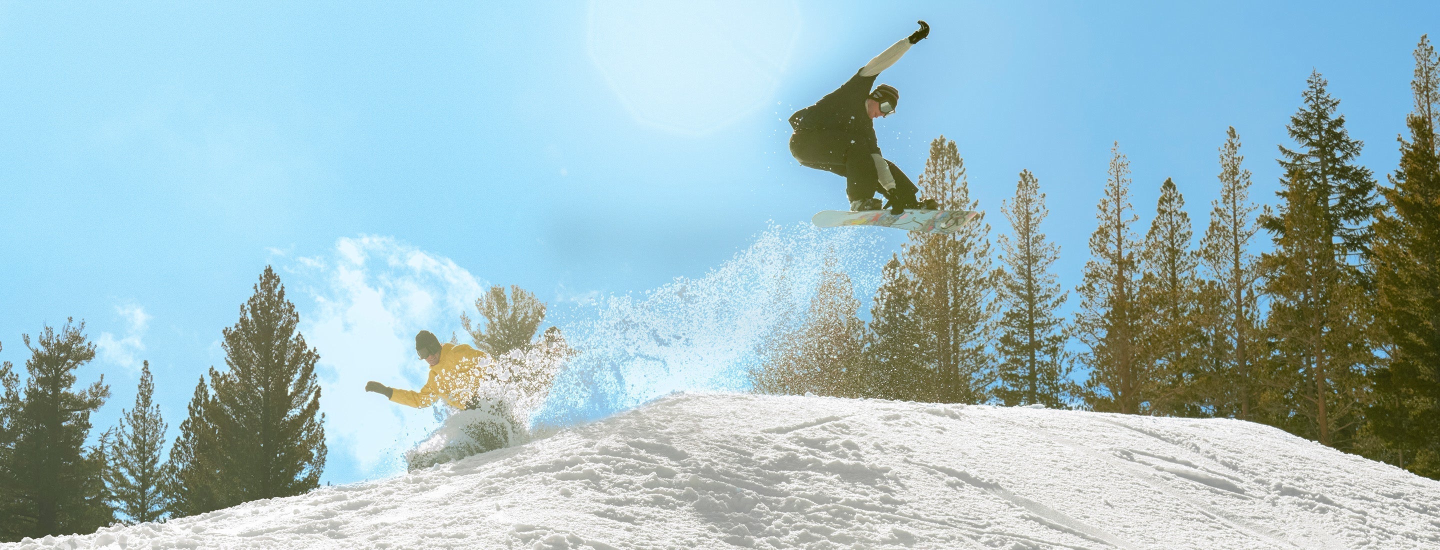 Two people snowboarding on a sunny day. 
