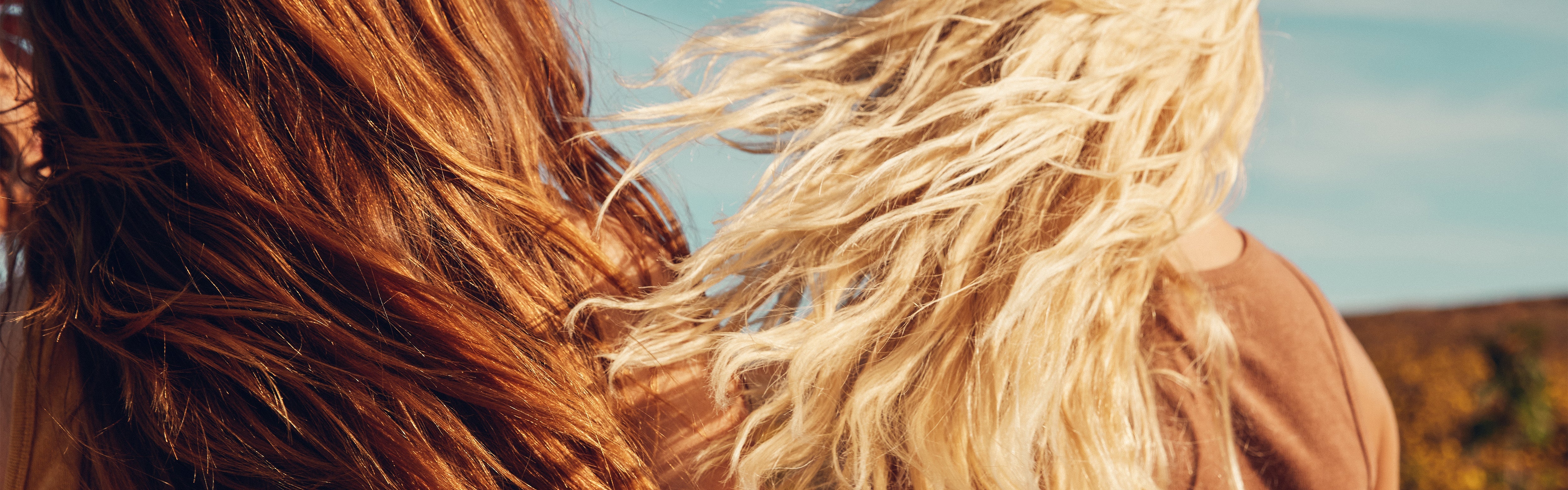 Close-up of sun-kissed, wind-blown hair outdoors, showcasing healthy shine from the SB Hair Care Collection – Sun Bum.