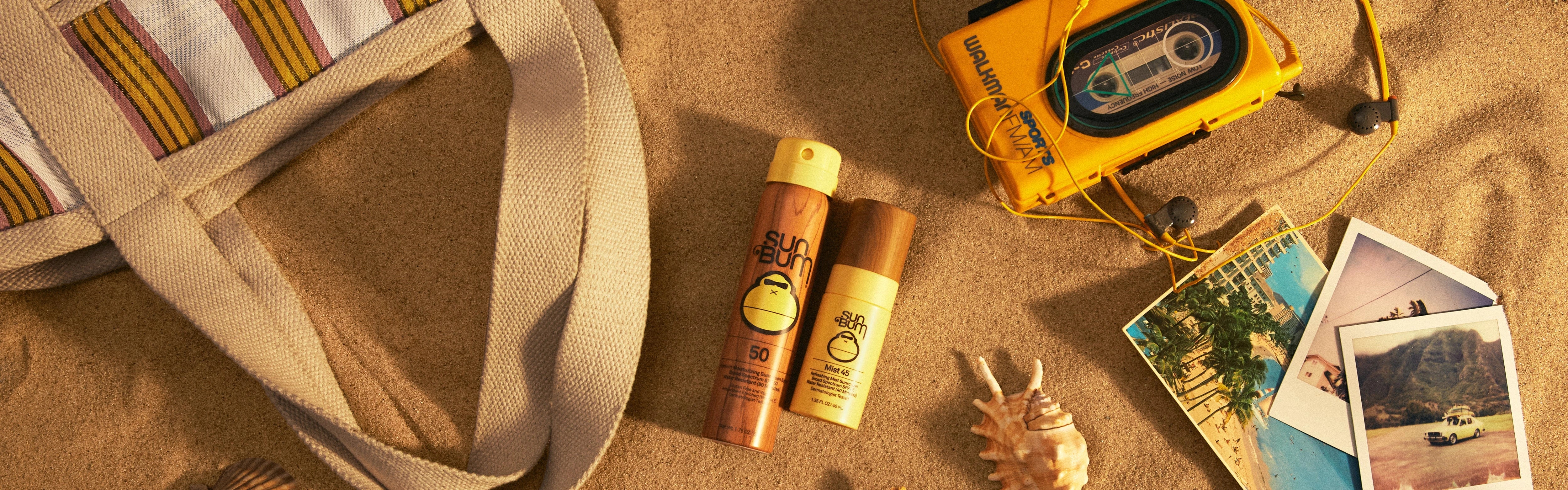 Flat lay of Sun Bum travel size sunscreen and face mist on beach sand with retro gear – Travel Size Sunscreen Collection - Sun Bum.