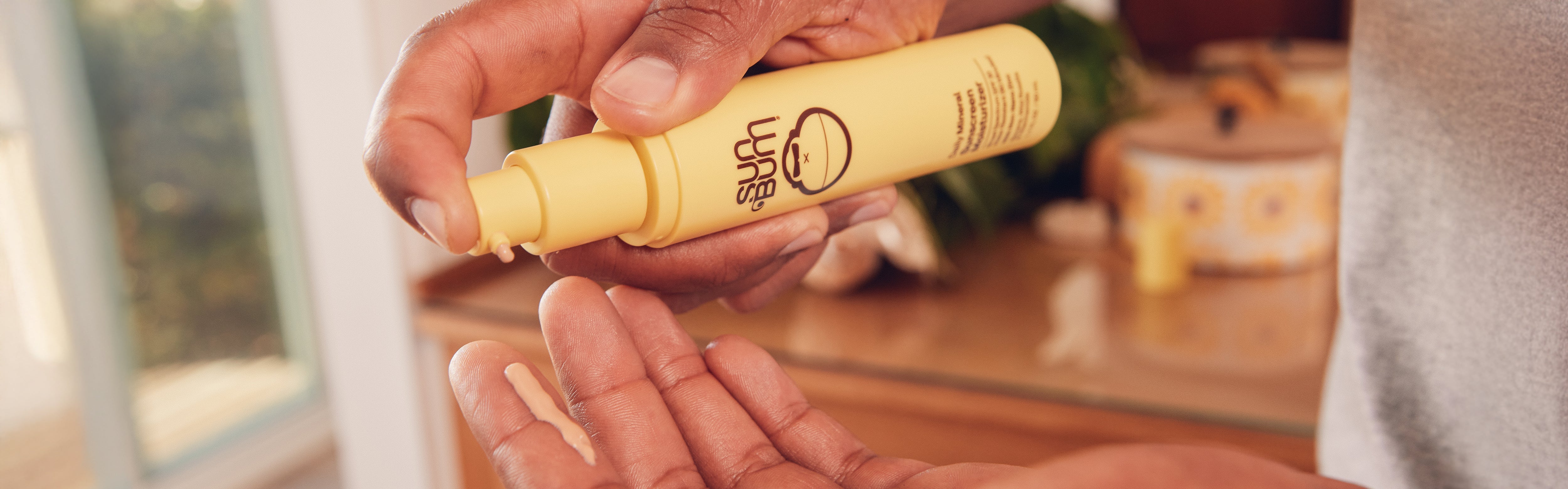 Close-up of hands dispensing face lotion from a yellow bottle, showcasing the SB Everyday Skin Care Collection – Sun Bum.