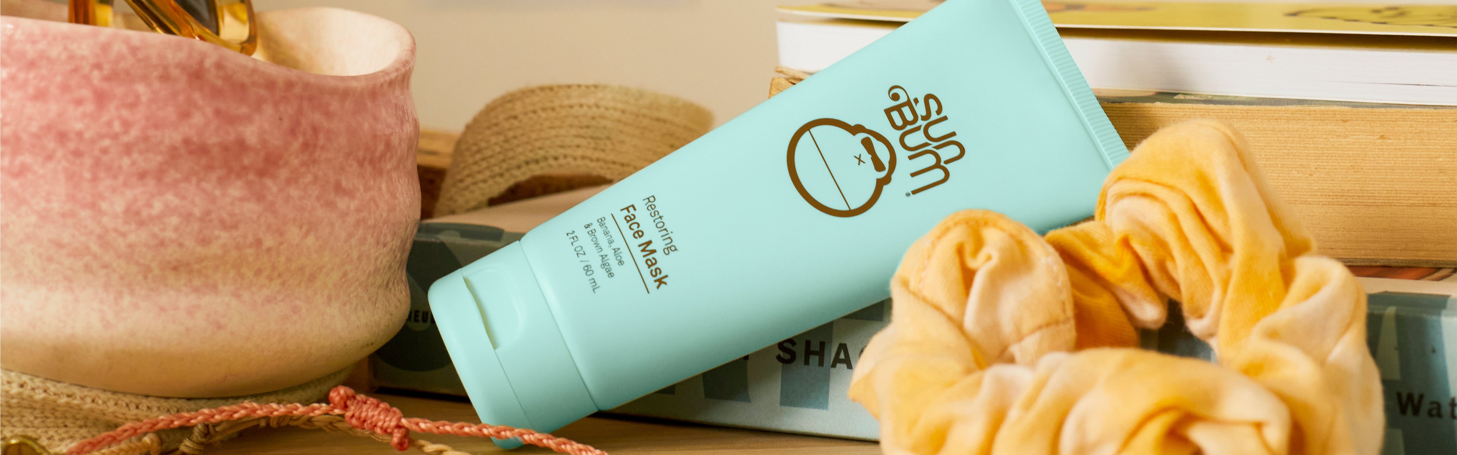 Sun Bum Restoring Face Mask on a desk with scrunchies and beachy decor, from the SB Restoring Skin Care Collection – Sun Bum.
