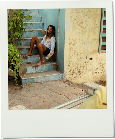 Man sitting on a staircase with a plant and wall in the background