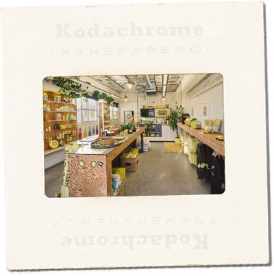 Kodachrome transparency slide showing a store interior with wooden counters and shelves.