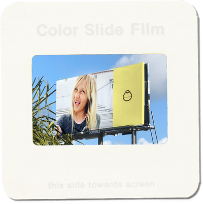 Color slide film with a photo of a woman on a billboard and a yellow box.