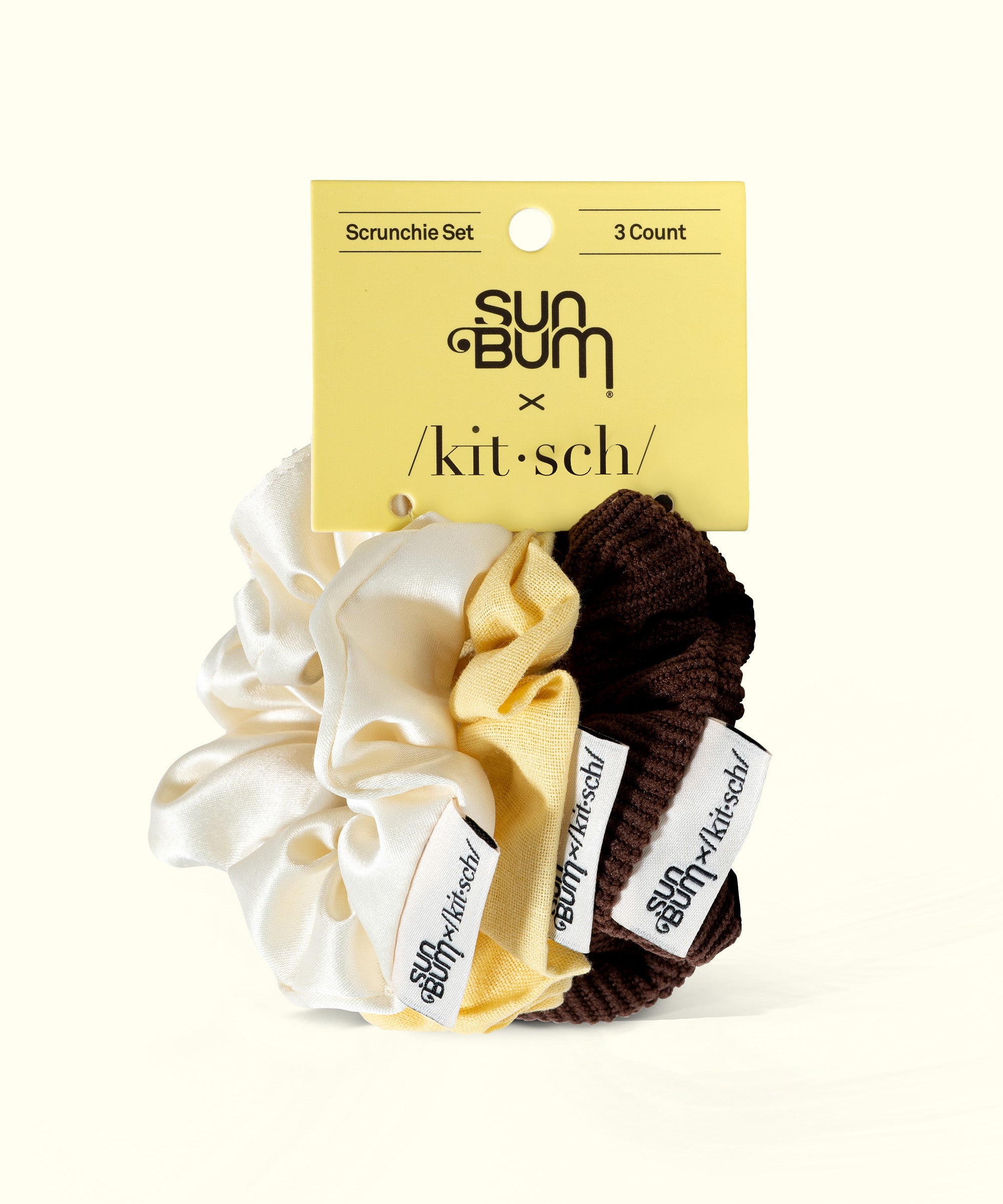 Limited Edition 3-piece Scrunchie Set featuring white, yellow, and brown fabric scrunchies with "Sun Bum" and "Kitsch" tags, Sun Bum