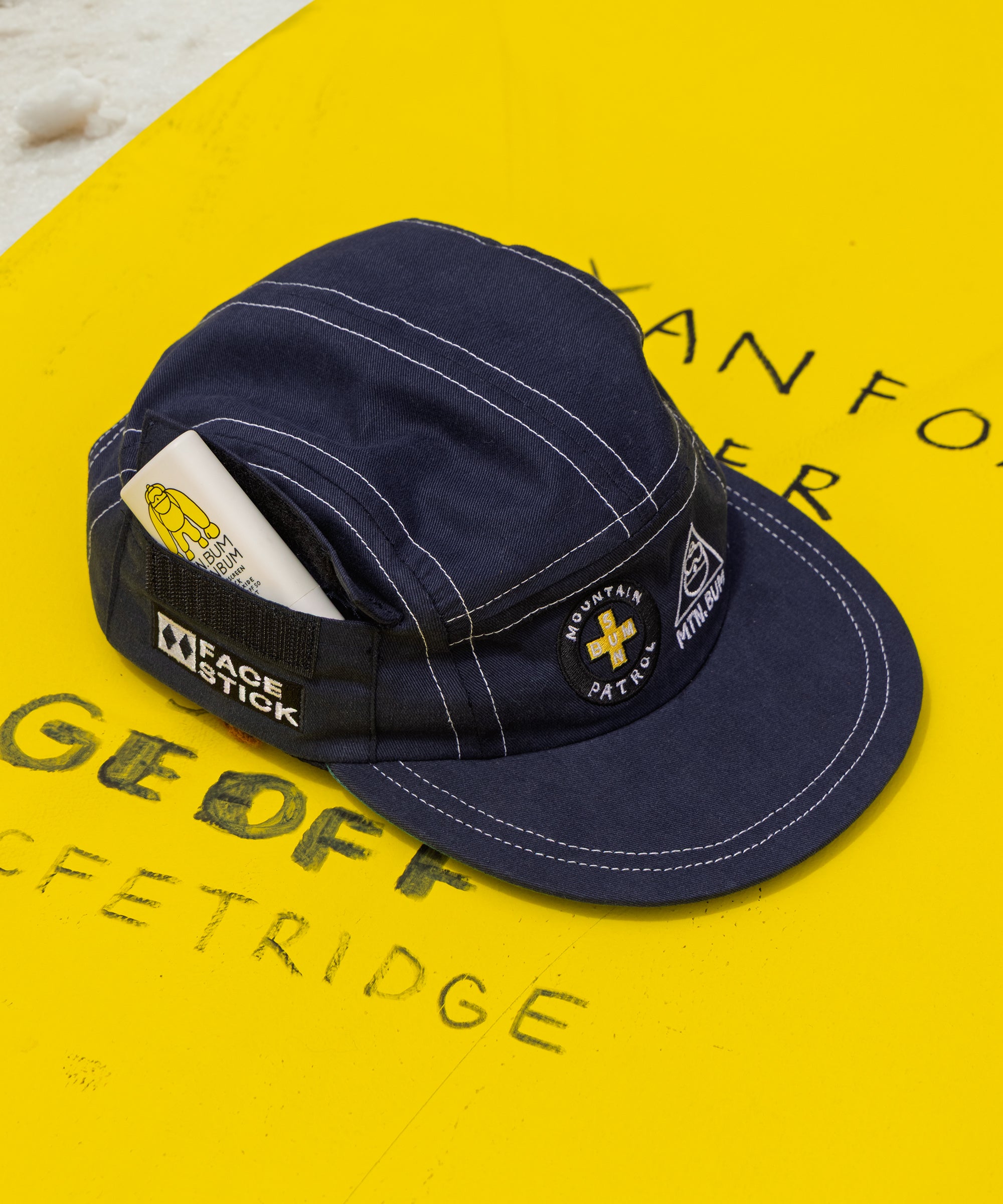 Navy cap with branding on a yellow surface with text