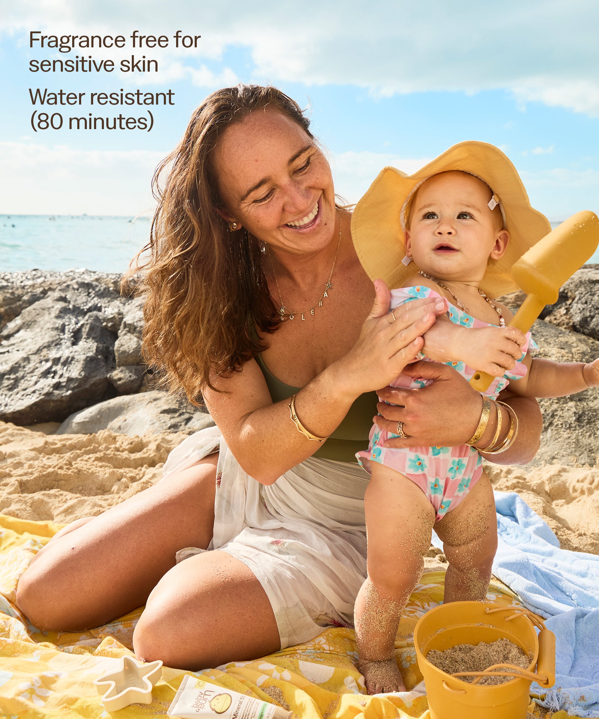 Woman holding a baby on a beach with text about product features.