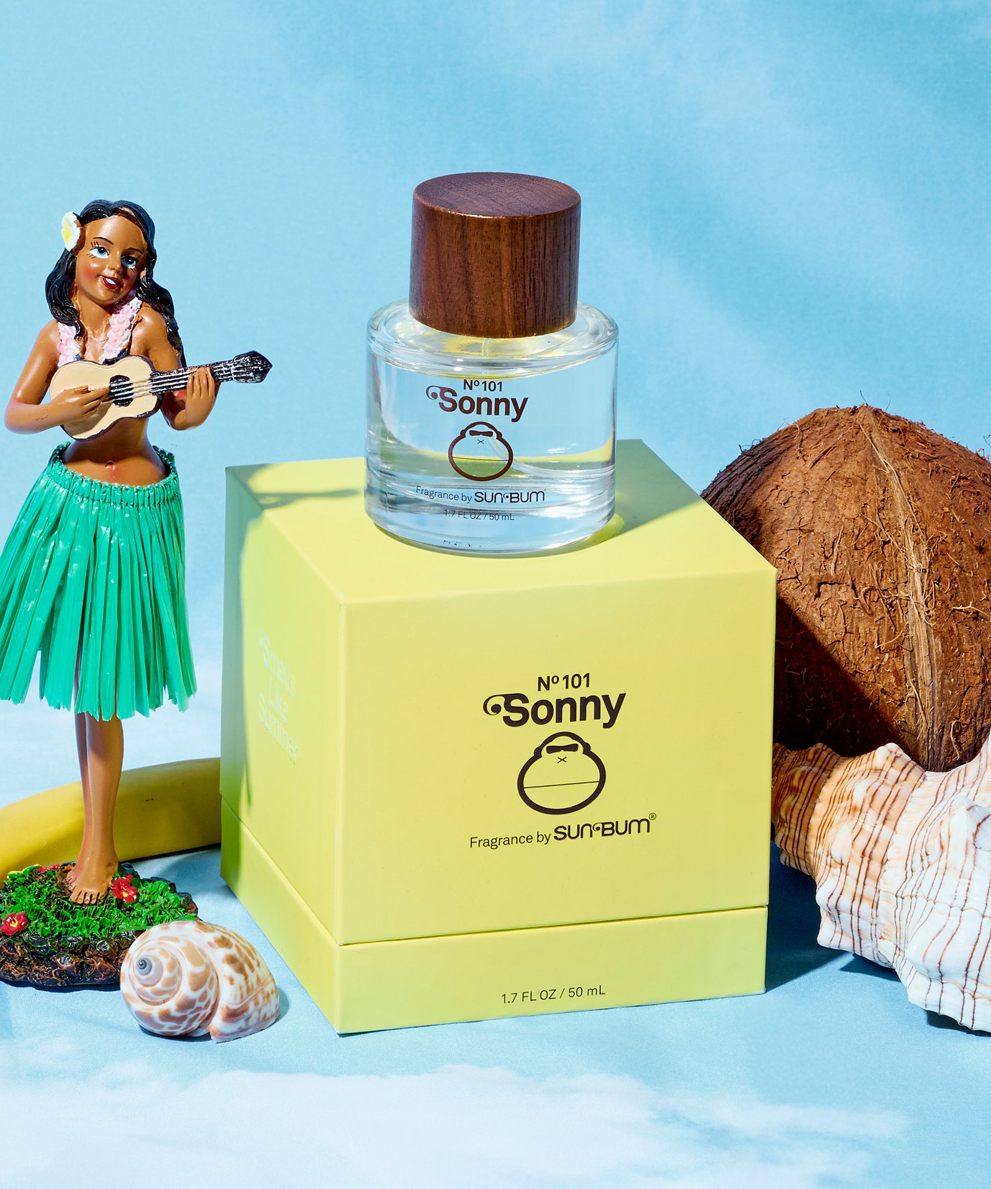 Perfume bottle labeled 'Sonny' by Sun Bum with packaging and beach-themed accessories on a blue background