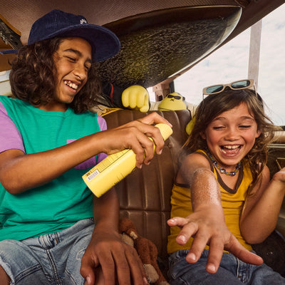 Kids laughing while applying SPF 50 Clear Spray Sunscreen with a lightweight formula – Kids Collection - Sun Bum