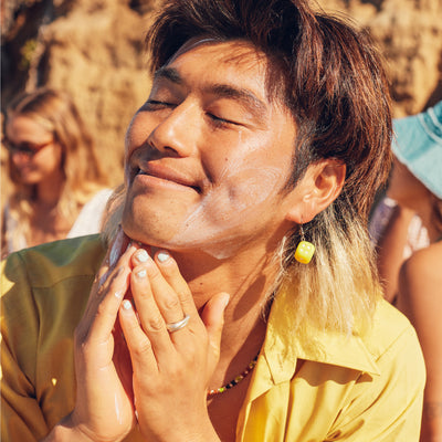 Man applying Sun Bum face sunscreen with SPF and Vitamin E, smiling in the sun with friends - Original SPF Collection - Sun Bum