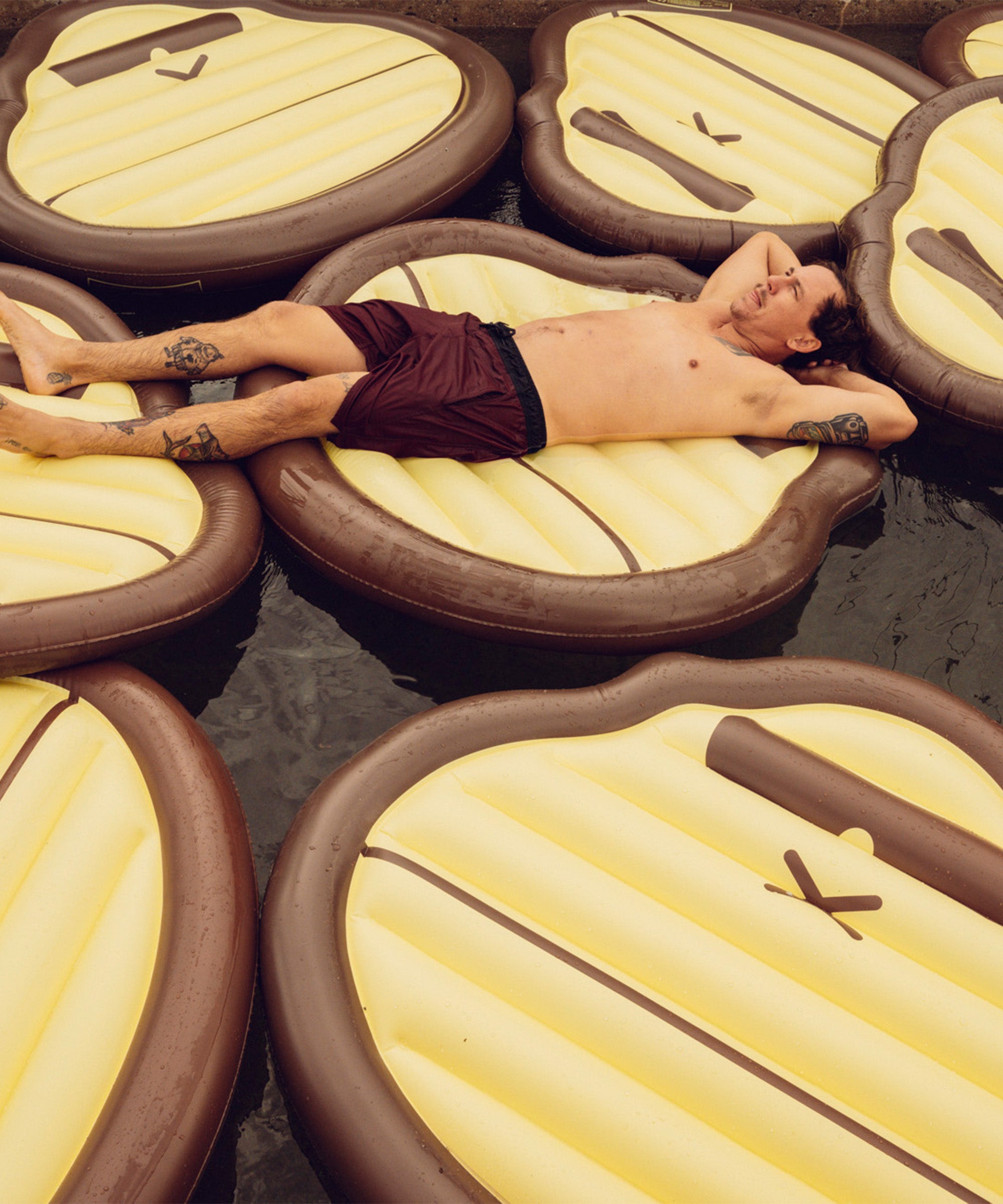 Man relaxing on multiple Sonny Pool Float water mattresses in a pool Sun Bum