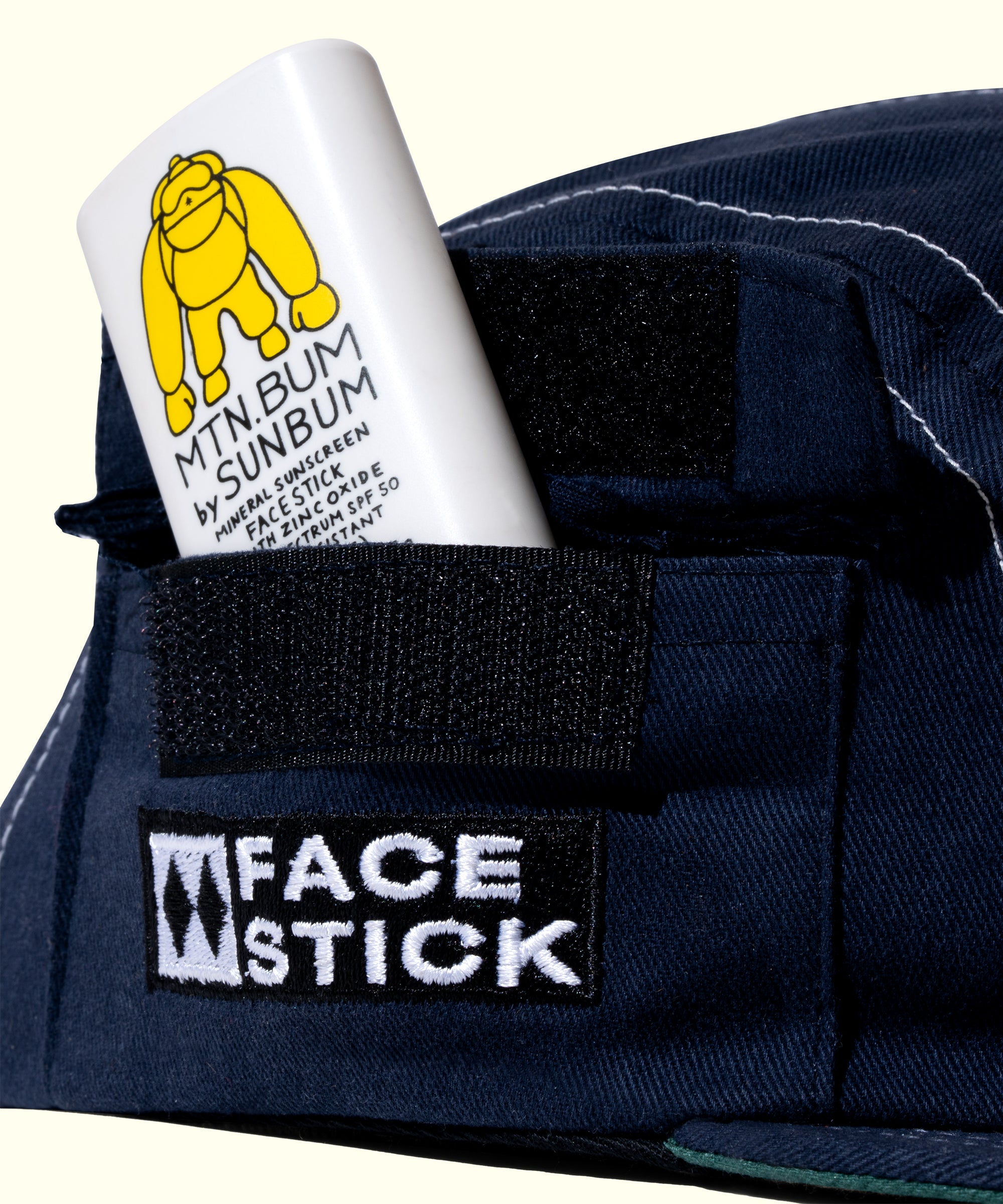 Navy blue cap with 'Face Stick' logo and a tube of sunscreen labeled 'Mtn Bum Sunbun' on a white background.