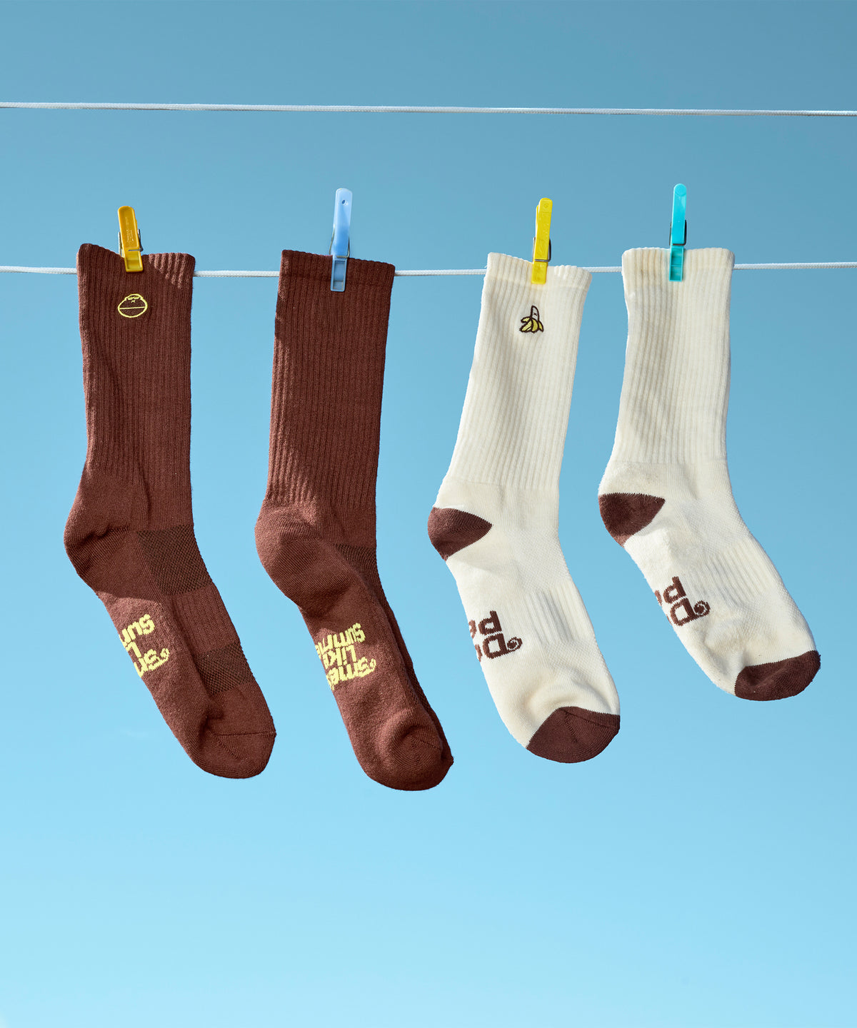 Brown and white socks on a clothesline in the blue sky.