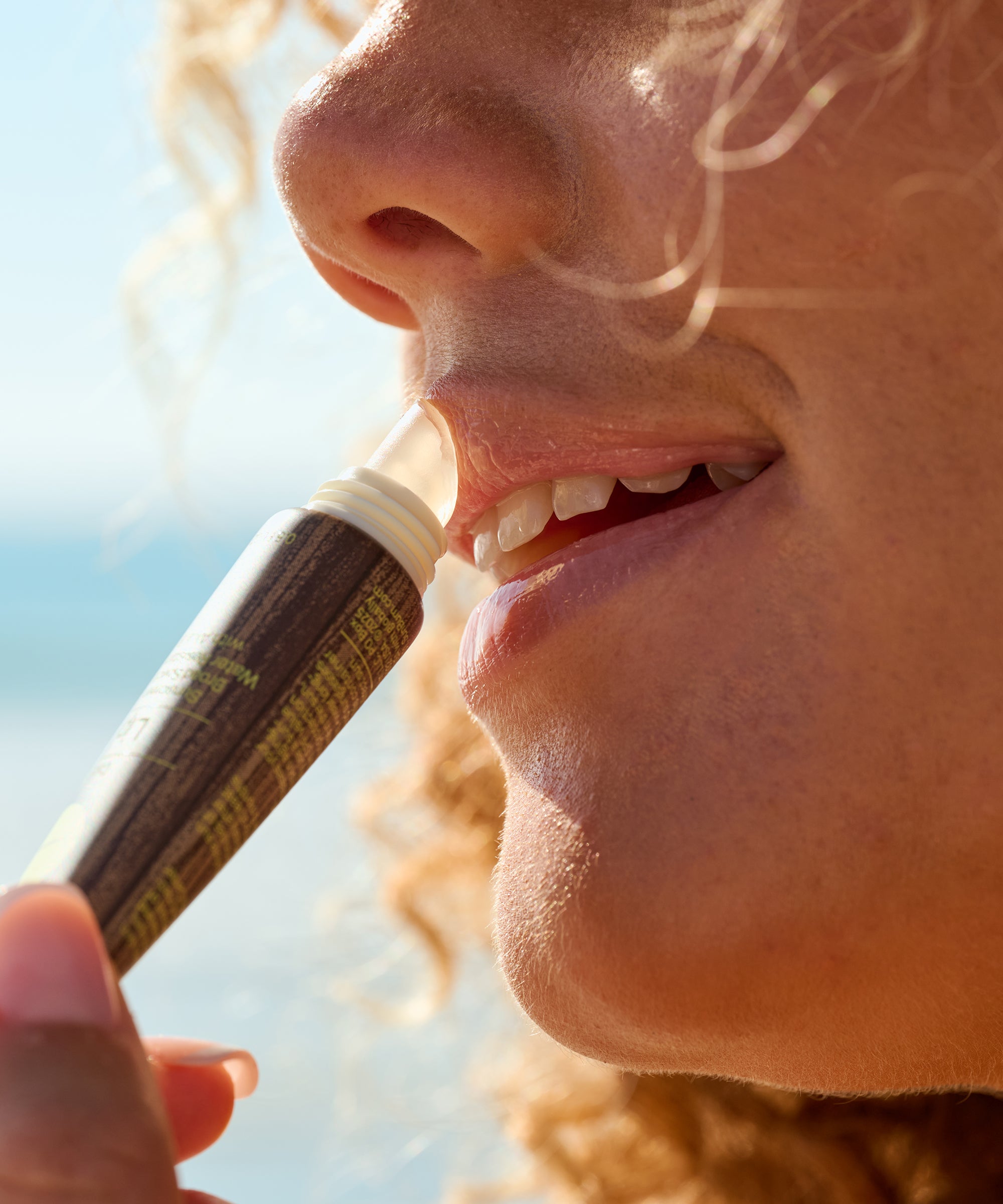 Close-up of a person using a lip balm with a blurred natural background