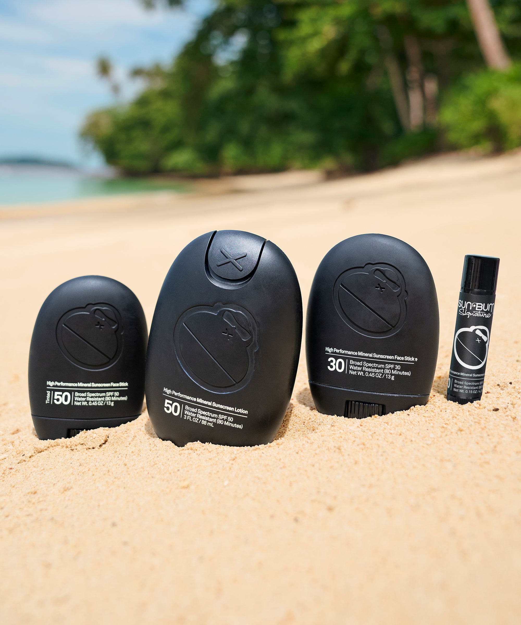 Set of sunscreen bottles on a sandy beach with a scenic background