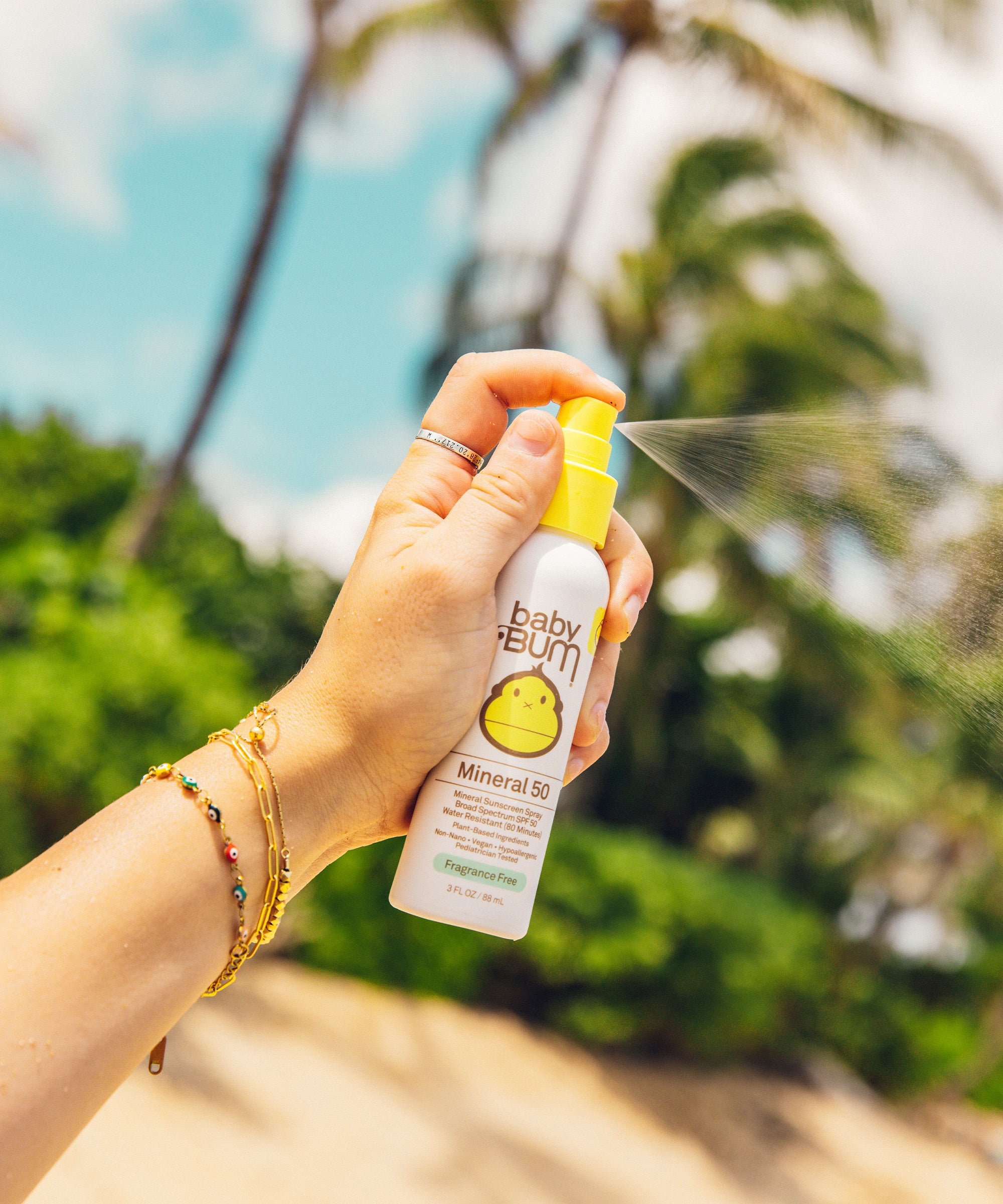 Hand spraying Baby Bum Mineral SPF 50 Sunscreen Spray with lightweight, non-greasy formula by Baby Bum
