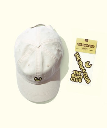 White cap with small banana logo and Bum Club Starter Pack sticker set by Sun Bum on light background