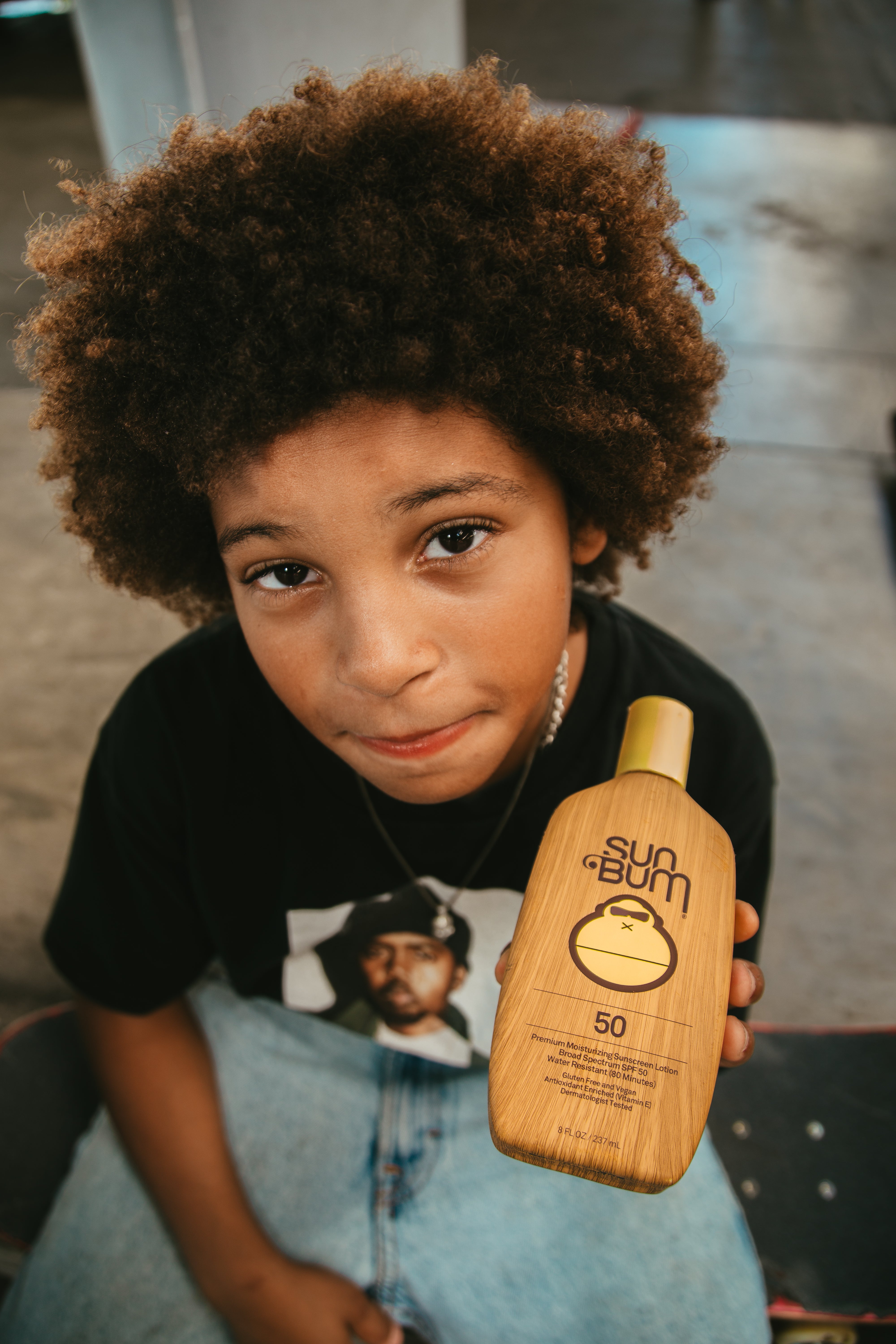 Child holding a bottle of Sun Bum sunscreen