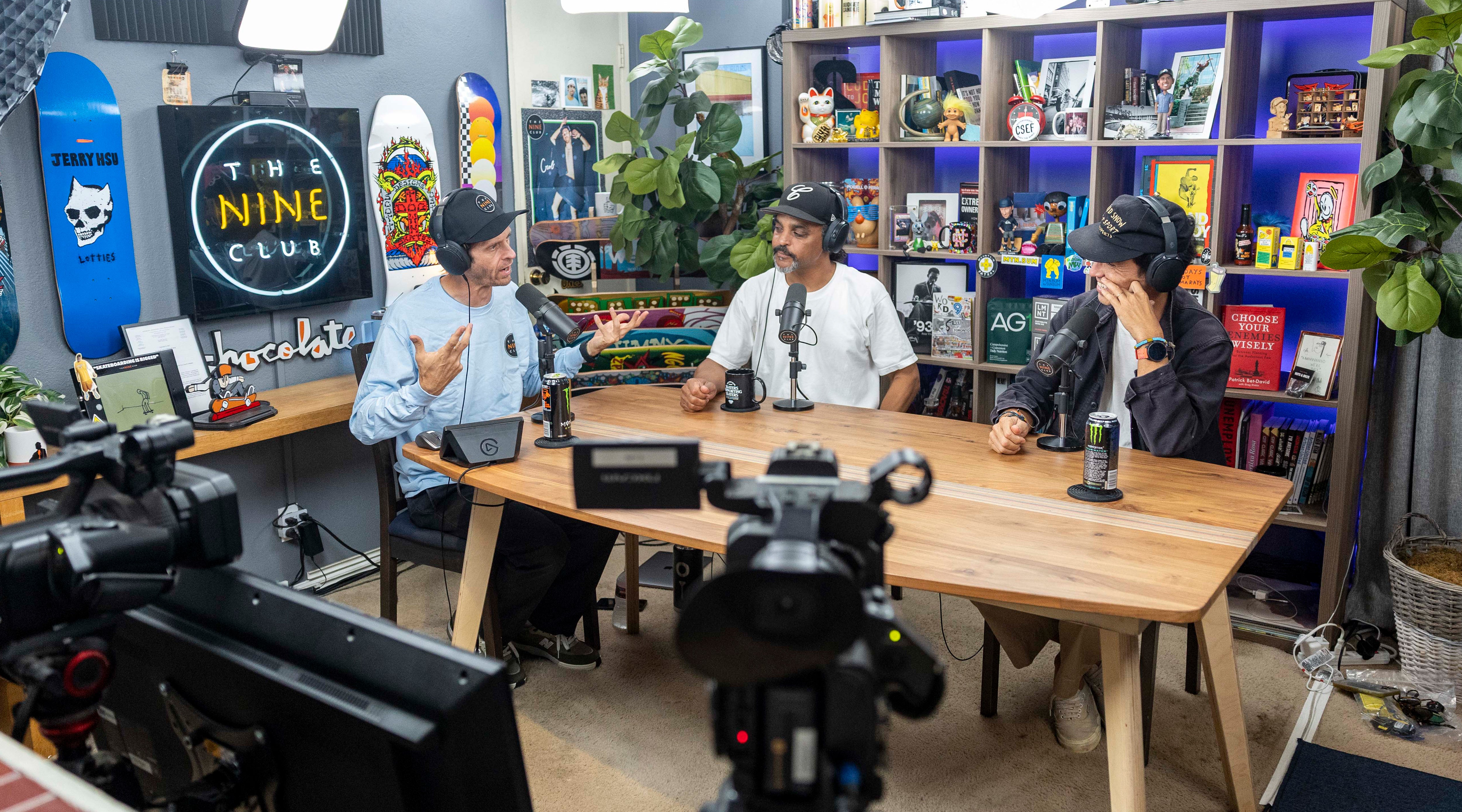 3 Men sitting around a table talking on a podcast.