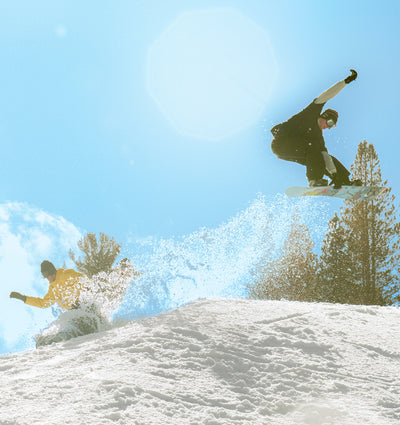 Two people snowboarding on a sunny day. 