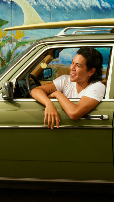 Man sitting in a car with a colorful mural in the background