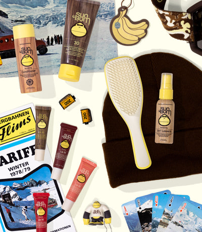 Collection of Sun Bum products including sunscreen, lip balm, and a paddle brush on a white background.