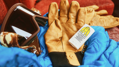 Brown leather gloves with a white label on a blue fabric background