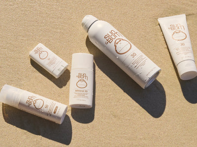 Sunscreen products on a beige sand background