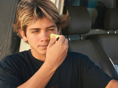 Person sitting in a car holding a yellow object to their ear