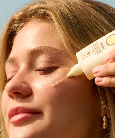 Person applying sunscreen to their face with a bottle labeled 'Every Day Sun'.