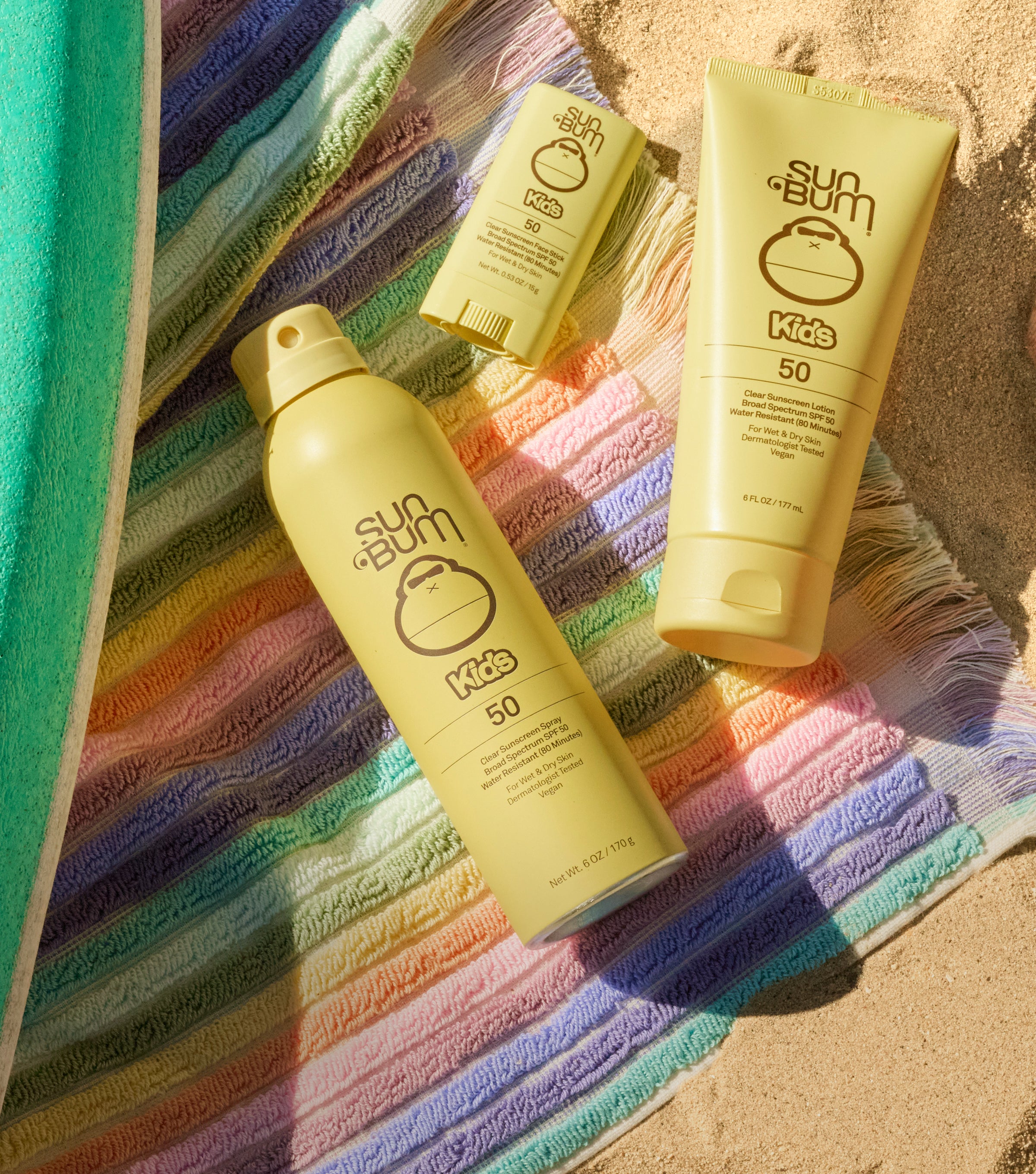 Sun Bum Kids sunscreen products on a colorful towel with sand in the background