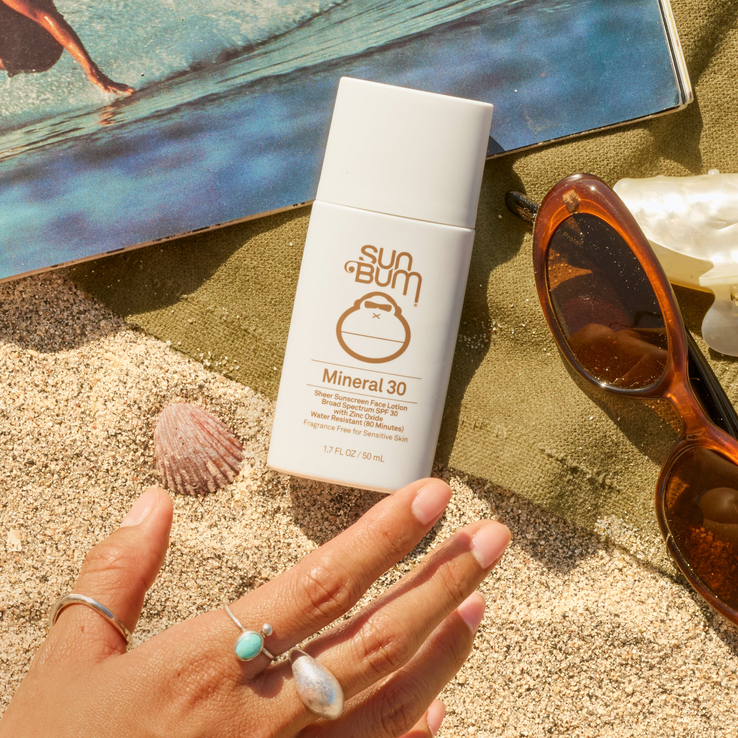 Sun Bum mineral sunscreen on a hand with beach background