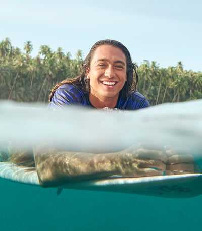 Person on a surf board in the water in a tropical setting