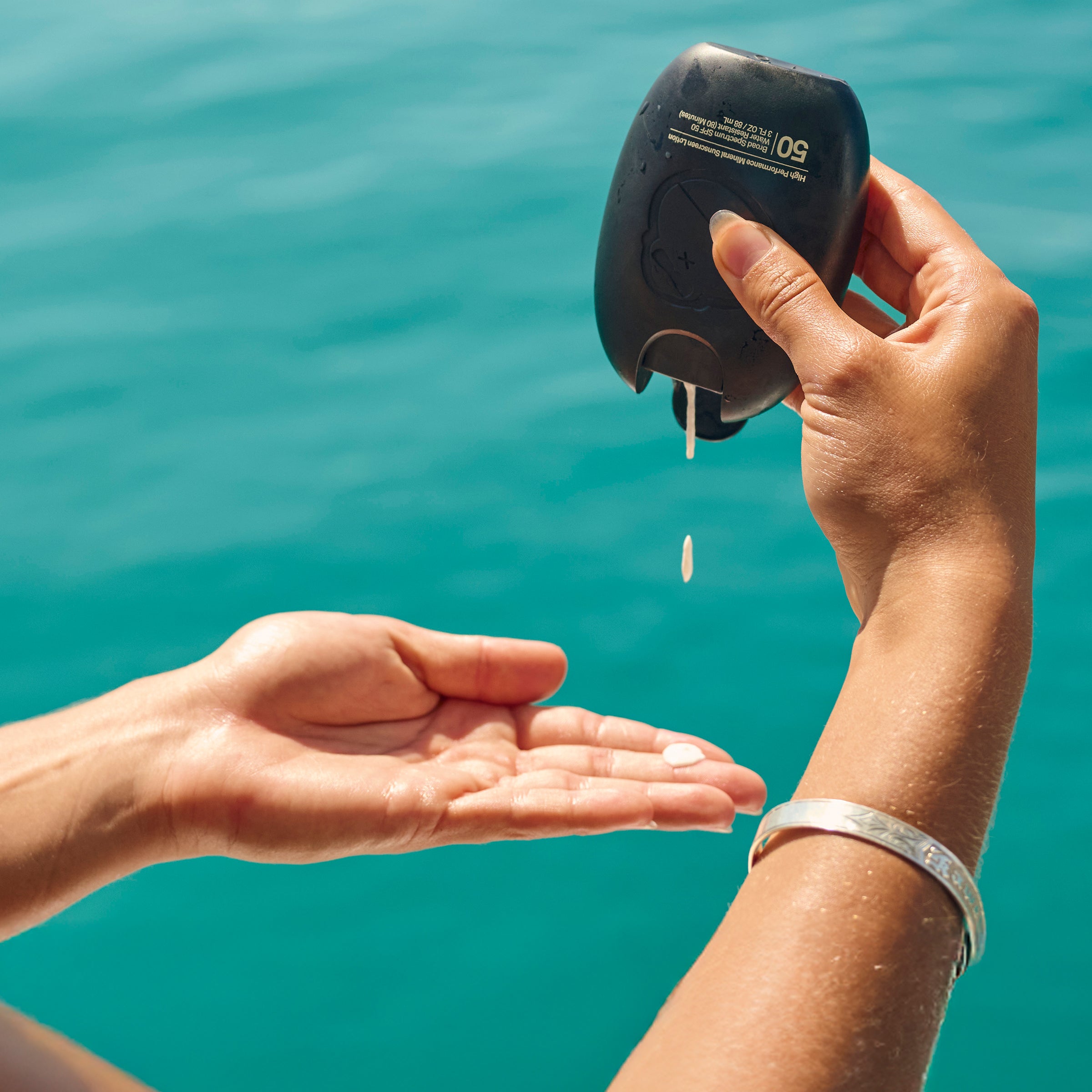 Sun Bum Signature lotion sunscreen being applied by the water