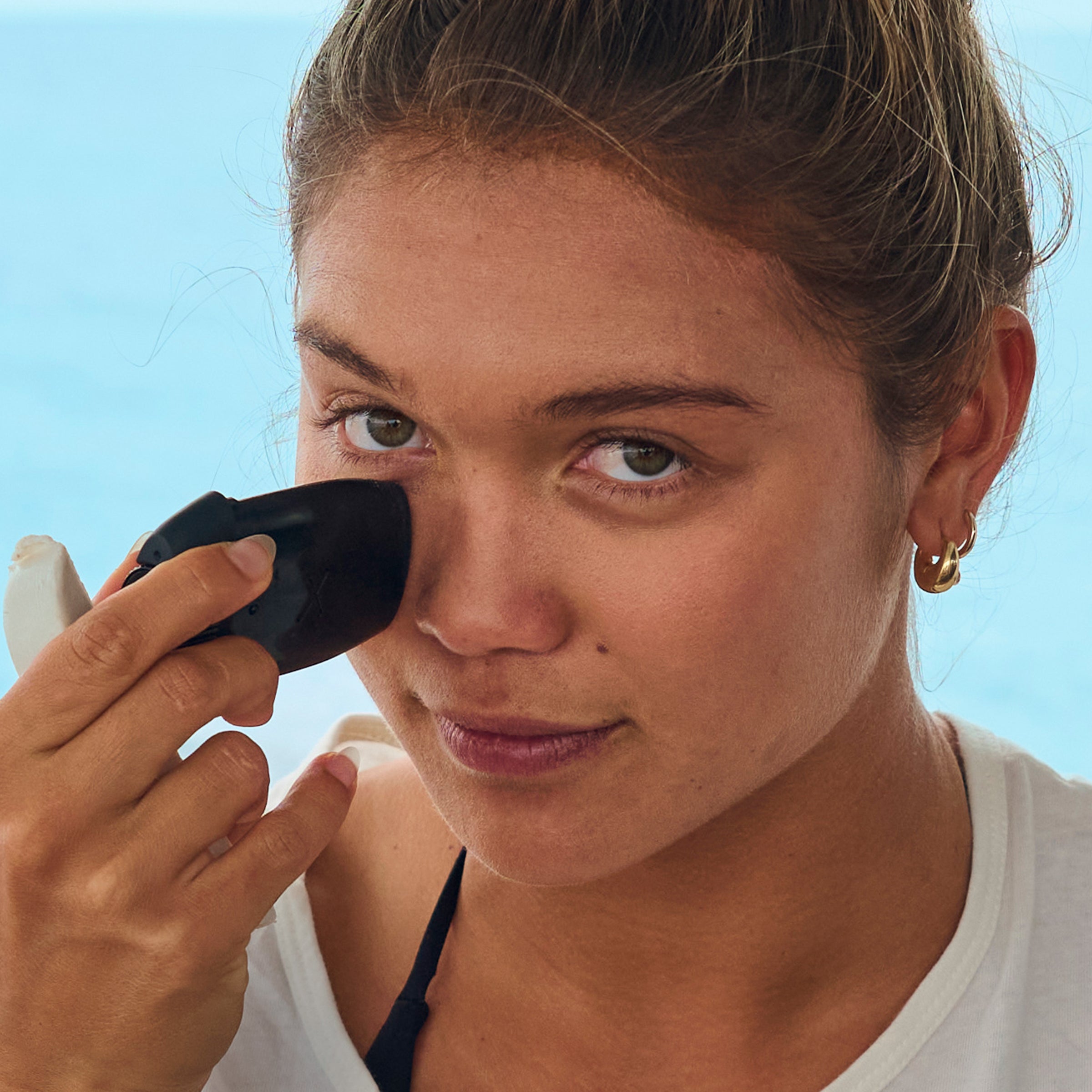 A woman using a sunscreen face stick