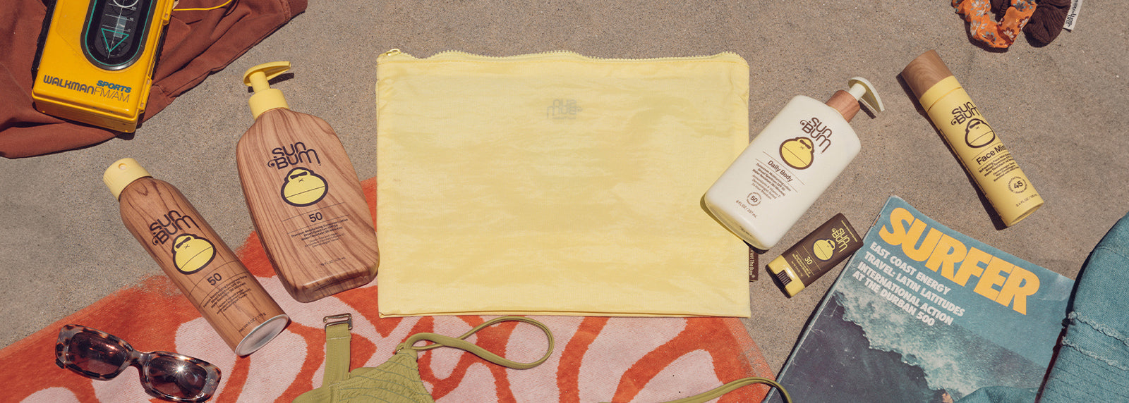 Flat lay of a yellow bag and Sun Bum products on the beach - Build Your Own Bag.