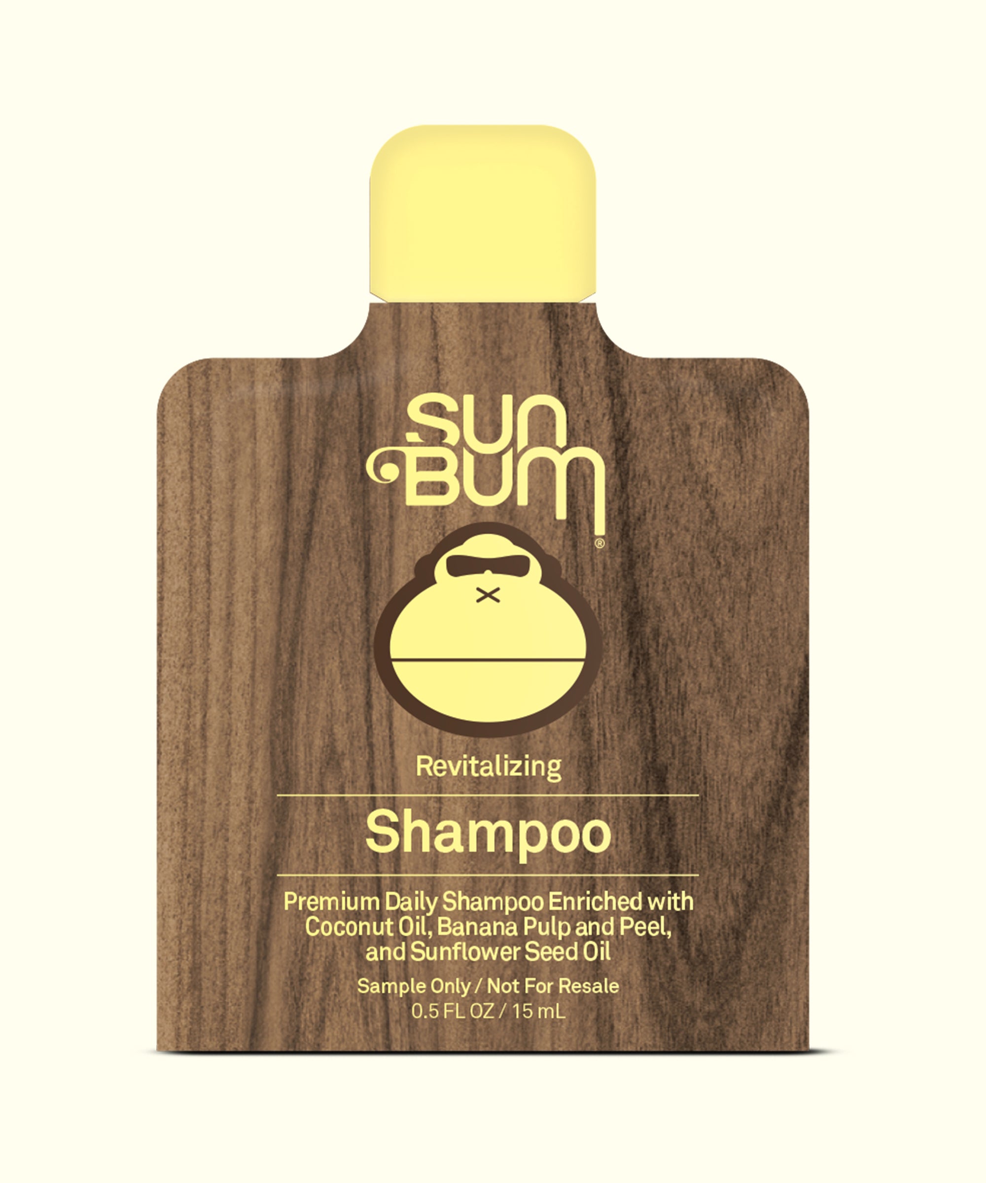 Sun Bum shampoo packet with wooden texture and yellow branding on a white background