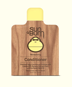 Sun Bum conditioner packet with wooden texture and yellow cap on a white background
