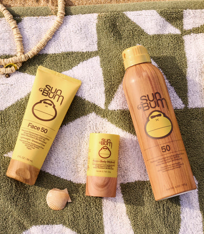 Sun Bum sunscreen essentials for face and body on a beach towel, from the Head to Toe Collection – Sun Bum.