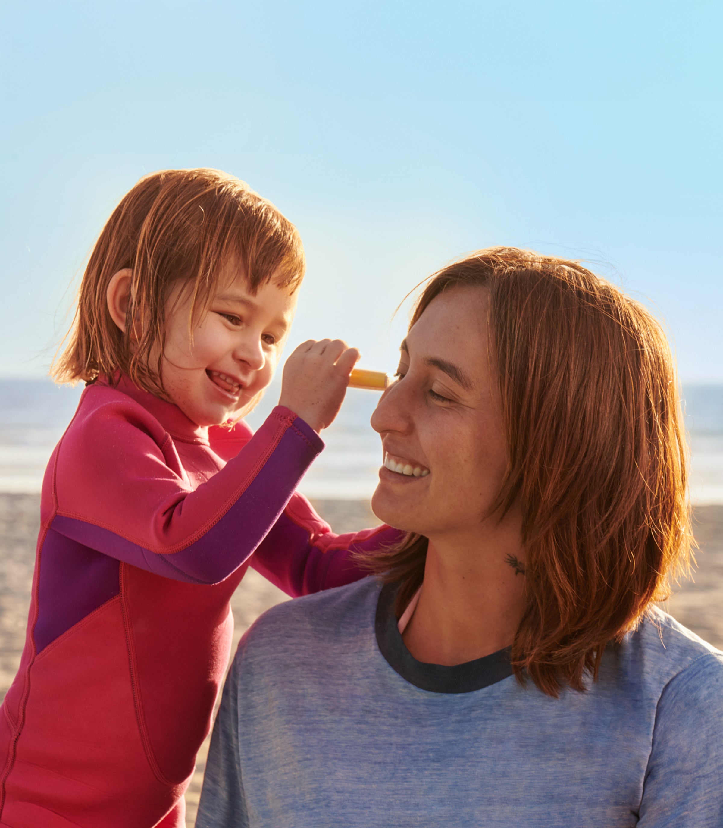 Smiling child applies sunscreen stick on parent’s nose at the beach – Sunscreen Sticks Collection - Sun Bum.