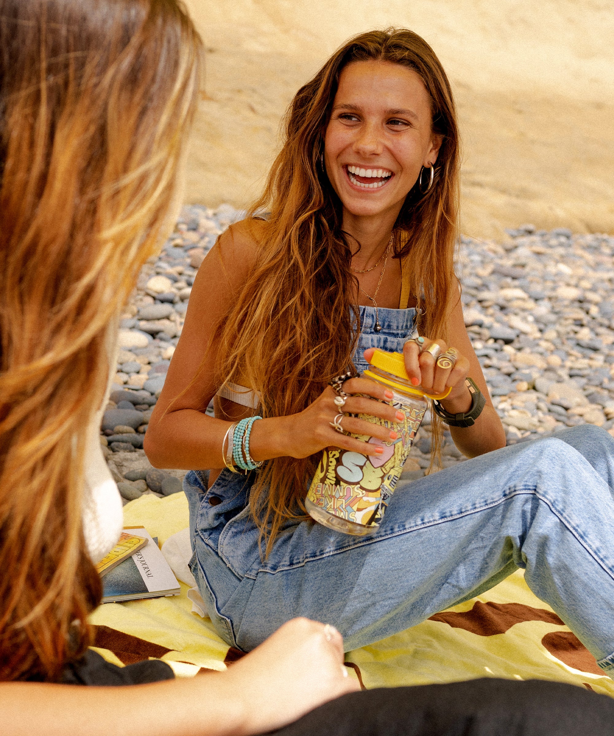 Smiling woman holds custom Sun Bum Nalgene water bottle while hanging at the beach - Sonny Gear Collection - Sun Bum